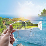 Fishing lure held by a hand with a scenic background of water and greenery.