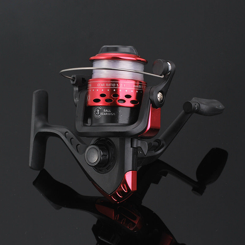 Fishing reel with red and black design on a reflective black surface