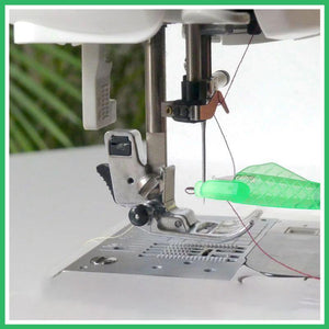 Close-up of a sewing machine needle and mechanism with a green background