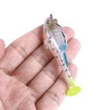 Transparent fishing lure with a yellow tail held in a hand against a white background