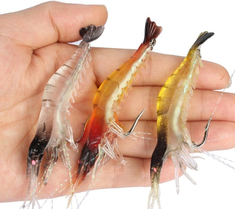 Three shrimp-shaped fishing lures held in a hand against a white background