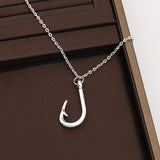 Silver fishing hook necklace on a brown surface