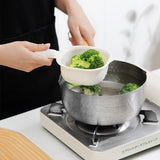Person adding broccoli into a pot of water on a stove