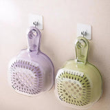 Two wall-mounted kitchen strainers, one purple and one green, on a light-colored wall.